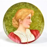 An Arts and Crafts circular wall charger, with hand painted decoration depicting a portrait of a