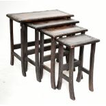 A nest of four Indonesian stained hardwood rectangular tables with carved foliate detail throughout,