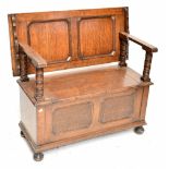 An early 20th century panelled oak monk's bench, raised on bun feet, height when closed 82cm, length