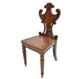 A Regency mahogany hall chair with foliate and scroll carved back on turned and tapered front