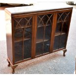 A mahogany bookcase with three astragal glazed doors enclosing an arrangement of shelves on cabriole