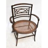 A 19th century Aesthetic Movement tub chair with carved back and cane seat on bamboo-effect