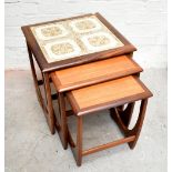 G-PLAN; A mid 20th century nest of three teak tables, the largest with inset floral tile top.