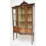 An Edwardian inlaid mahogany bow front display cabinet with twin glazed doors enclosing two fixed