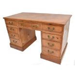 A stained pine knee hole desk with an arrangement of nine drawers, raised on a plinth base, height
