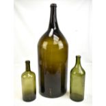 A very large 19th century green glass wine bottle, height approx 60cm, and two smaller examples (