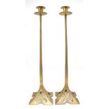 A pair of Arts & Crafts style brass candlesticks with pierced decoration to the bases, height 56cm.