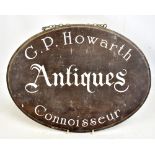 A vintage oval wooden sign inscribed 'G.P.Howarth Antiques Connoisseur' with chain link hanging