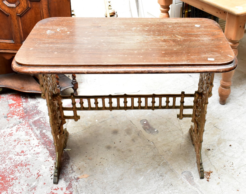A Victorian cast iron framed table with later oak top, the base with pierced floral detail, height