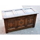 A stained oak coffer, the hinged lid with three fielded panels above foliate carved panelled front