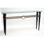 A contemporary console table with frosted glass top above a black iron frame with gilt highlights,