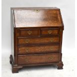 An oak and mahogany cross banded bureau, the fall front enclosing fitted interior, above two short