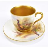 JAMES STINTON FOR ROYAL WORCESTER; a hand painted teacup and saucer, decorated with pheasant in