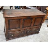 A stained oak blanket chest, the three-panel front with carved grotesque mask to centre flanked by