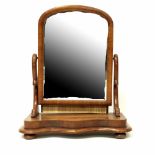 A Victorian mahogany swivel toilet mirror with scroll side supports on stepped serpentine base.