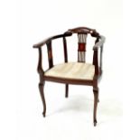 An Edwardian mahogany inlaid tub chair with upholstered seat, raised on cabriole legs to peg feet.