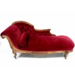 A Victorian walnut-framed chaise longue upholstered in red button-back velour,