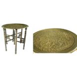 A Benares-type tray top table, brass charger with embossed detail of figures and foliage,