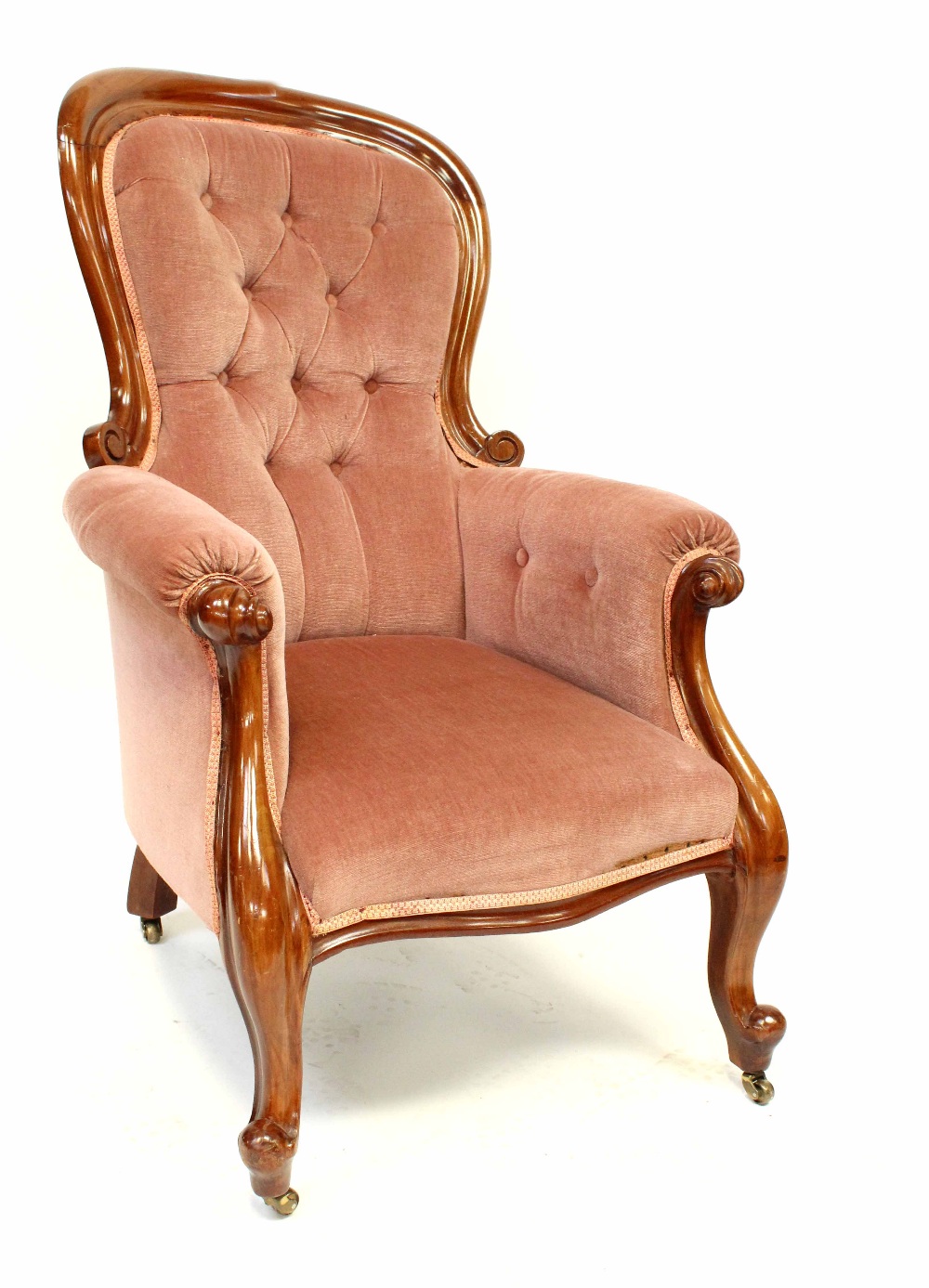 A Victorian mahogany fireside chair upholstered in pink button-back velvet, on carved cabriole legs,