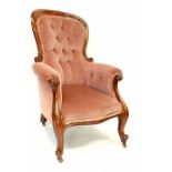 A Victorian mahogany fireside chair upholstered in pink button-back velvet, on carved cabriole legs,