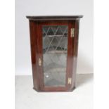 A Georgian mahogany wall-hanging corner cupboard with dentil moulded cornice above leaded glazed