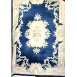 A modern Chinese thick pile rug with a floral central panel on a deep blue ground with beige floral