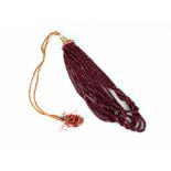 A ruby bead eight-row necklace, the graduated faceted beads on a woven-thread sliding knot clasp,