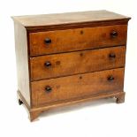 An early 19th century tiger fleck oak chest of drawers with shaped top above three long drawers and