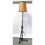 A brass standard lamp converted to electricity with three outswept scrolling supports,