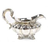 An early 19th century hallmarked silver cream jug with high loop handle, gadrooned main body and