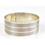 CHARLES HORNER; a George VI hallmarked silver bangle in the form of a belt, with engine turned