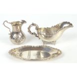 A sterling silver sauce boat and stand, with cast scrolling detail to the edges, each piece with