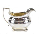 A George III hallmarked silver cream jug of oval form with bead decorated rim, simple loop handle