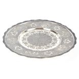 TAGHI PASHOOTAN; an Iranian white metal salver raised on three ball feet, with cast floral rim and