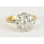 An 18ct yellow gold and white metal set diamond daisy cluster ring, the central stone weighing