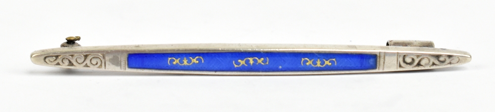 A white metal and blue enamel decorated bar brooch with gilt heightening to the panel of enamel,
