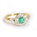 An 18ct yellow gold and platinum tipped emerald and diamond ring, the central emerald weighing