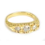 An 18ct yellow gold three stone diamond ring, the central stone weighing approx 0.25cts in scroll