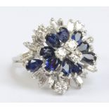 An 18ct white gold diamond and sapphire stepped cocktail ring with ten sapphires within a frame of