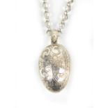 A silver chain suspending a white metal egg shaped pendant, length of chain approx 68cm, combined