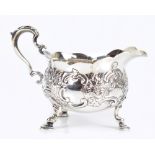 WALTER & JOHN BARNARD; a late Victorian hallmarked silver cream jug with embossed decoration, loop