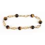 A yellow metal and tiger's eye beaded bracelet, with seven tiger's eye beads, length 20cm.Additional