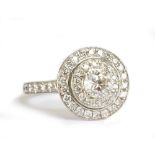 JENNY PACKHAM; an 18ct white gold and diamond stepped target ring with central brilliant cut stone