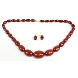A cherry amber graduated necklace and pair of matching drop earrings, size of the largest bead
