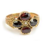 An Edwardian 15ct yellow gold garnet and pearl ring with engraved details to the shoulders,