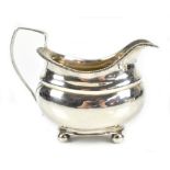 A George III hallmarked silver cream jug of bellied oval form with bead decorated rim, simple loop