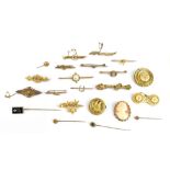 A large group of yellow metal brooches, tie and stick pins including a circular leaf decorated