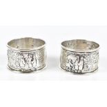 G EDWARDS & SON; a pair of white metal napkin rings, with repoussé and chased detail depicting