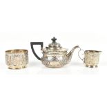 A Victorian hallmarked silver harlequin three piece bachelor's service, the teapot with repoussé