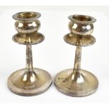 WALKER & HALL; a pair of Edwardian hallmarked loaded silver candlesticks with shaped bowls, swept